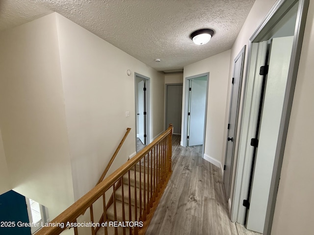 1512 Lindy Dr, Lansing, MI 48917 - hall featuring an upstairs landing, light wood-style floors, a textured ceiling, and baseboards