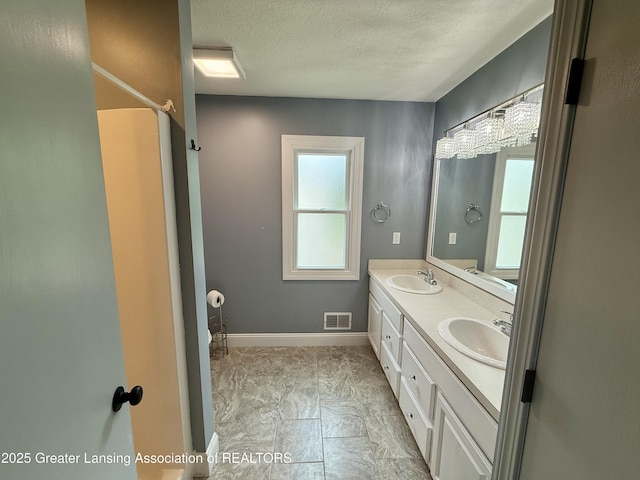 1512 Lindy Dr, Lansing, MI 48917 - full bath with double vanity, a textured ceiling, and baseboards