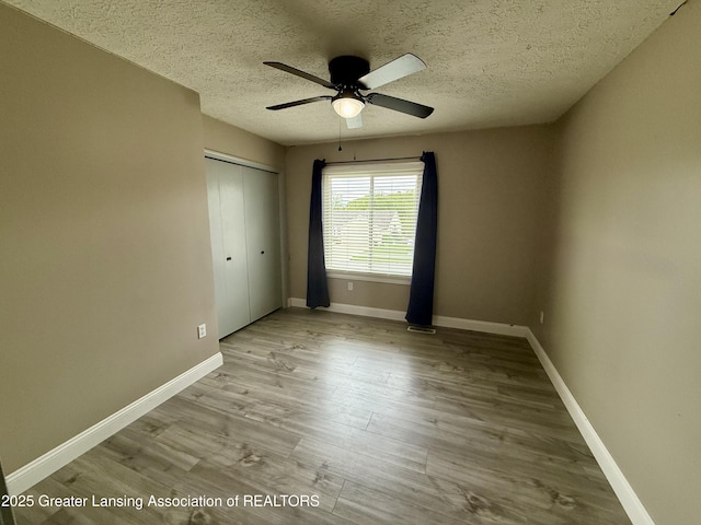 1512 Lindy Dr, Lansing, MI 48917 - unfurnished bedroom with a textured ceiling, a closet, wood finished floors, baseboards, and a ceiling fan