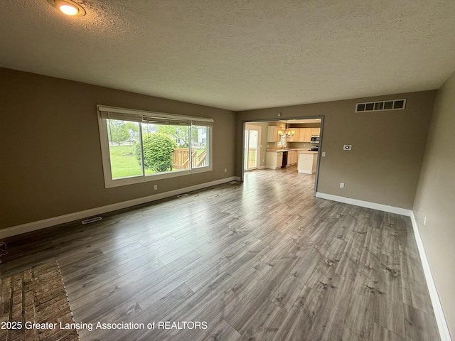 1512 Lindy Dr, Lansing, MI 48917 - unfurnished living room with a textured ceiling, wood finished floors, and baseboards
