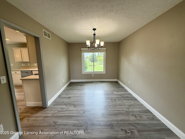 1512 Lindy Dr, Lansing, MI 48917 - unfurnished dining area with wood finished floors, a chandelier, a textured ceiling, and baseboards