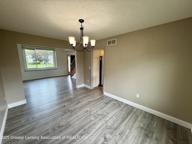 1512 Lindy Dr, Lansing, MI 48917 - unfurnished dining area featuring a chandelier, light wood-style flooring, baseboards, and a textured ceiling