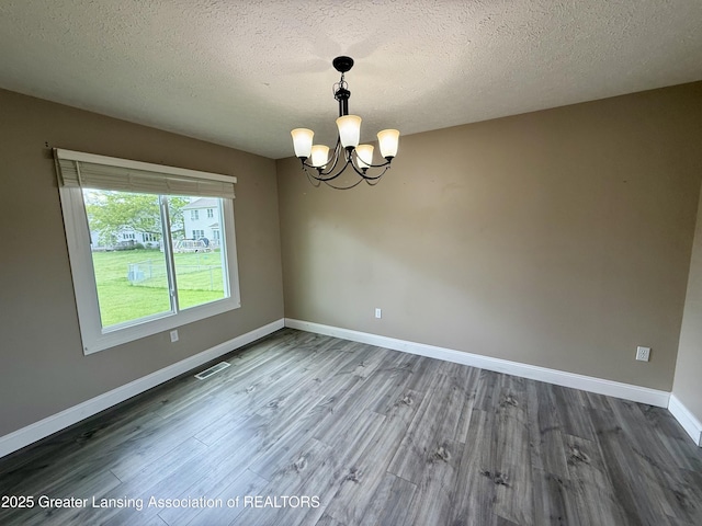 1512 Lindy Dr, Lansing, MI 48917 - unfurnished room featuring a chandelier, wood finished floors, baseboards, and a textured ceiling
