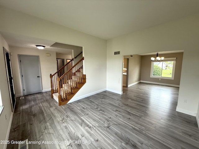 1512 Lindy Dr, Lansing, MI 48917 - unfurnished living room with a chandelier, stairs, wood finished floors, and baseboards