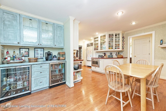 4767 Mohican Ln, Okemos, MI 48864 - dining space with wine cooler, a dry bar, ornamental molding, light wood-style floors, and recessed lighting