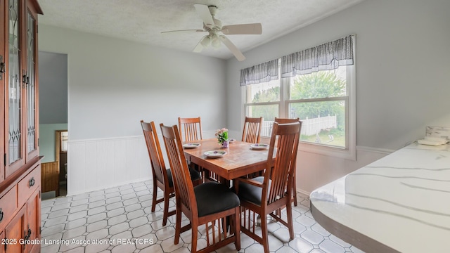515 Chanticleer Trl, Lansing, MI 48917 - dining space with wainscoting, a ceiling fan, a textured ceiling, and light floors