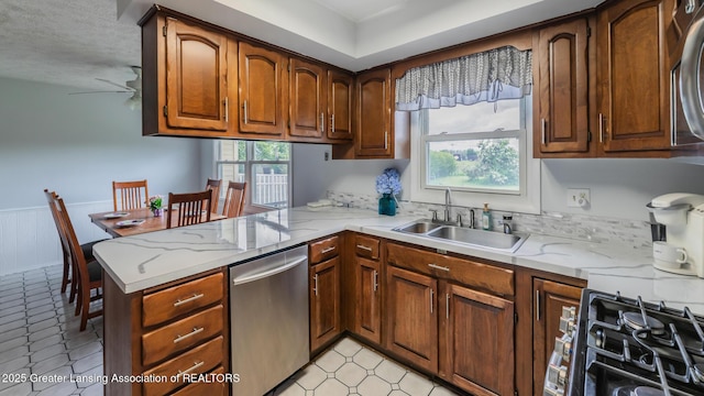 515 Chanticleer Trl, Lansing, MI 48917 - kitchen featuring dishwasher, a sink, a peninsula, a wainscoted wall, and gas range