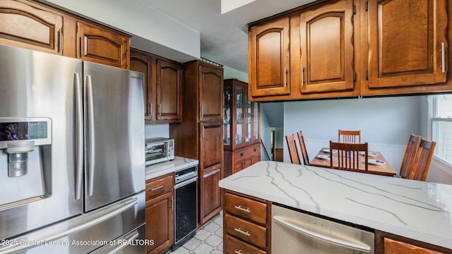 515 Chanticleer Trl, Lansing, MI 48917 - kitchen with stainless steel appliances, light stone counters, and brown cabinetry