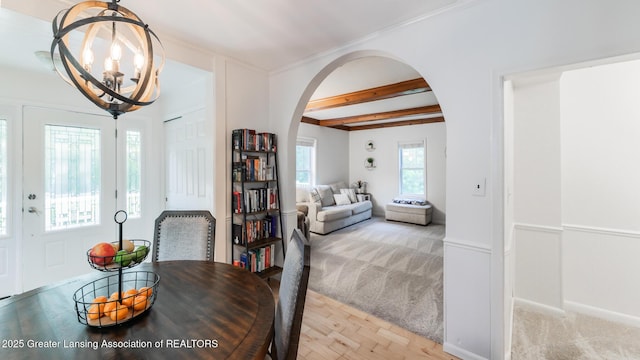 9181 Coleman Rd, Haslett, MI 48840 - dining space featuring arched walkways, a chandelier, light colored carpet, beamed ceiling, and light wood-type flooring