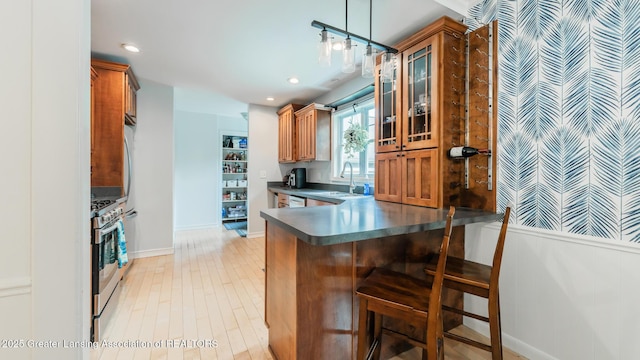 9181 Coleman Rd, Haslett, MI 48840 - kitchen with dark countertops, brown cabinetry, a sink, stainless steel range with gas stovetop, and glass insert cabinets