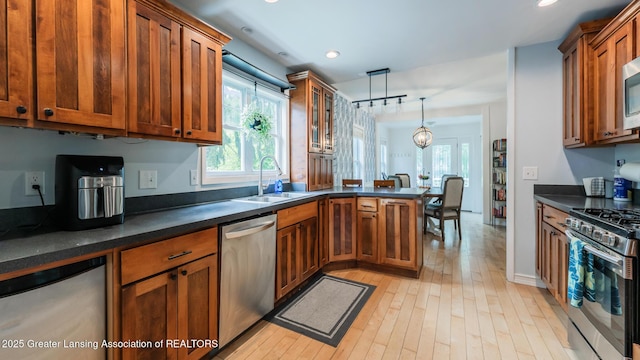 9181 Coleman Rd, Haslett, MI 48840 - kitchen featuring stainless steel appliances, a sink, brown cabinetry, a peninsula, and light wood-style flooring