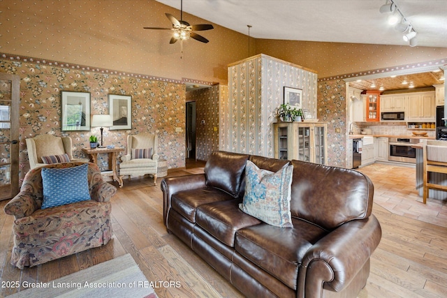 12560 Eaton Rapids Rd, Springport, MI 49284 - living room with track lighting, wallpapered walls, ceiling fan, light wood-style flooring, and high vaulted ceiling