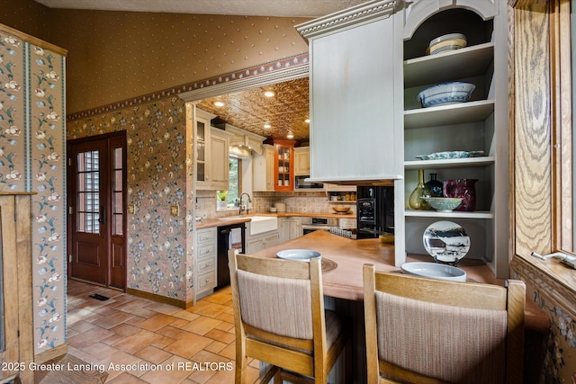 12560 Eaton Rapids Rd, Springport, MI 49284 - kitchen with black dishwasher, wallpapered walls, a sink, glass insert cabinets, and light countertops