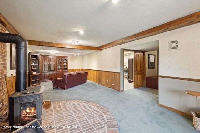 12560 Eaton Rapids Rd, Springport, MI 49284 - living room featuring carpet, a textured ceiling, wainscoting, a wood stove, and wood walls