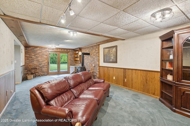 12560 Eaton Rapids Rd, Springport, MI 49284 - carpeted living area featuring a wood stove, a wainscoted wall, and wooden walls