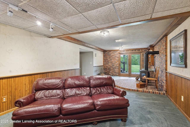 12560 Eaton Rapids Rd, Springport, MI 49284 - carpeted living room with wood walls, a wood stove, and wainscoting