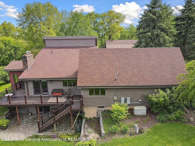 12560 Eaton Rapids Rd, Springport, MI 49284 - rear view of property featuring a shingled roof, a wooden deck, stairway, a chimney, and a patio area