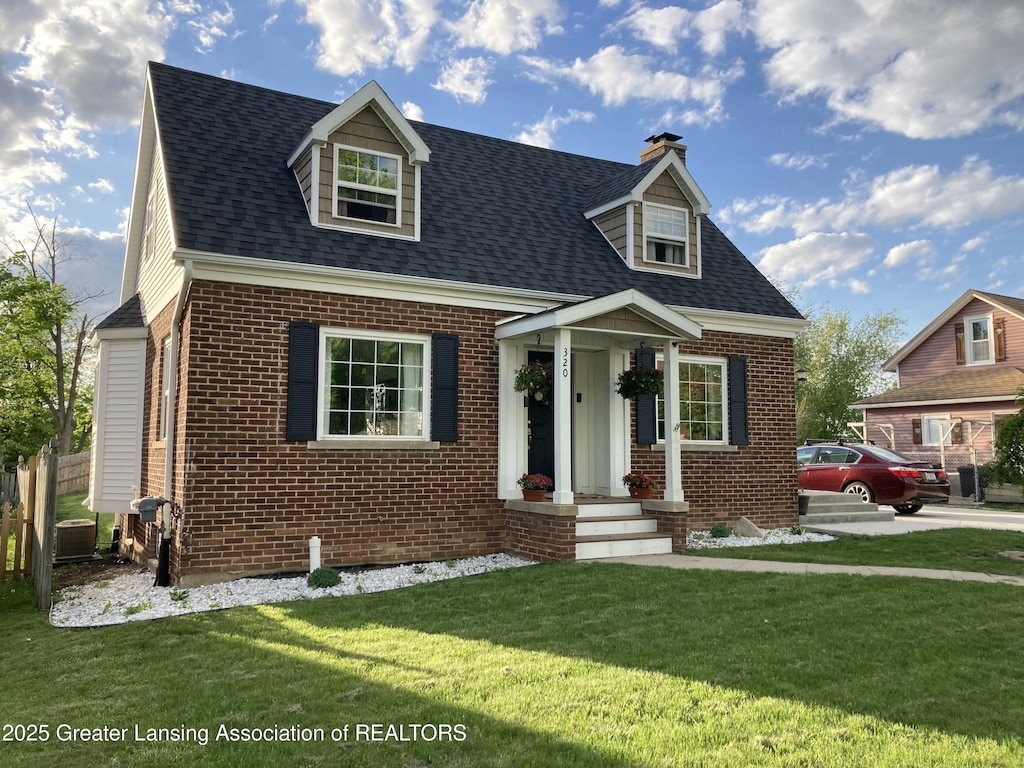 320 Elm St, Portland, MI 48875 - cape cod house with brick siding, central AC, a chimney, and a front yard