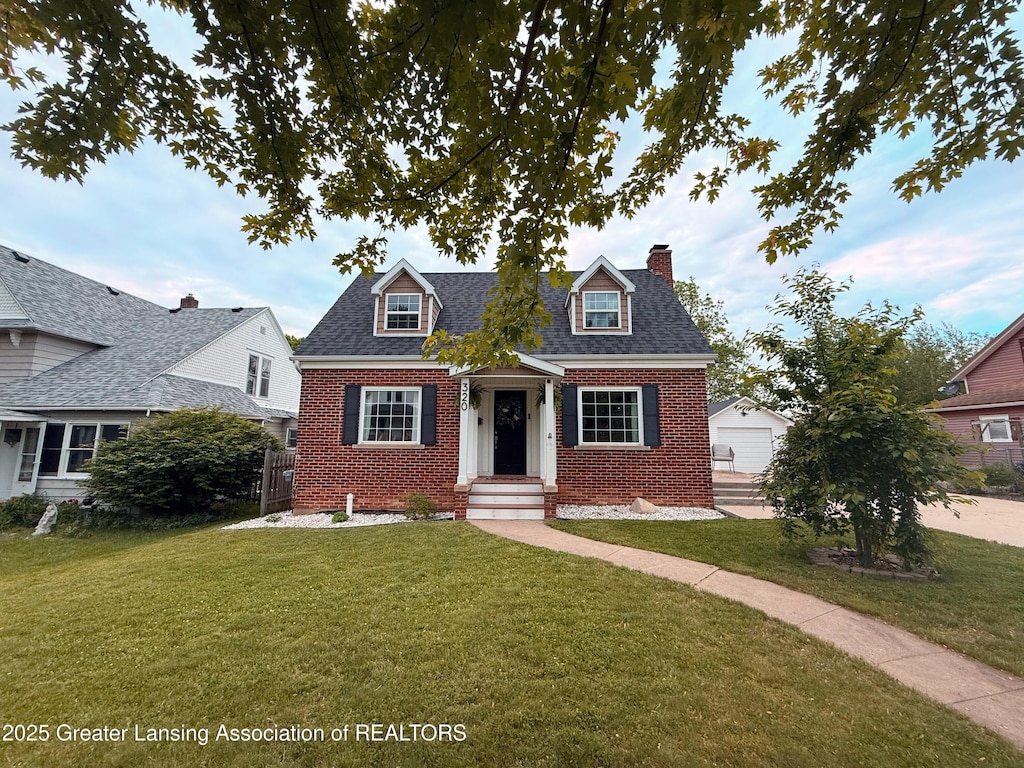 320 Elm St, Portland, MI 48875 - new england style home with brick siding, a chimney, an outdoor structure, and a shingled roof