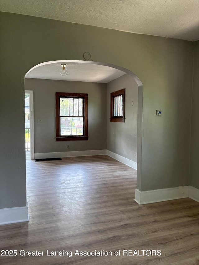 2113 S Rundle Ave, Lansing, MI 48910 - spare room featuring arched walkways, wood finished floors, baseboards, and a textured ceiling