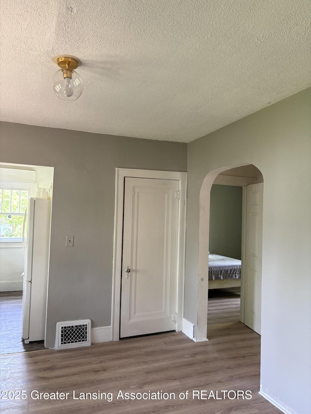 2113 S Rundle Ave, Lansing, MI 48910 - hallway with wood finished floors, arched walkways, a textured ceiling, and baseboards