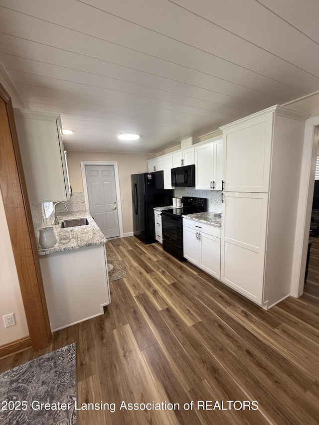 4412 Darron Dr, Lansing, MI 48917 - kitchen with black appliances, a sink, dark wood finished floors, white cabinets, and light stone counters