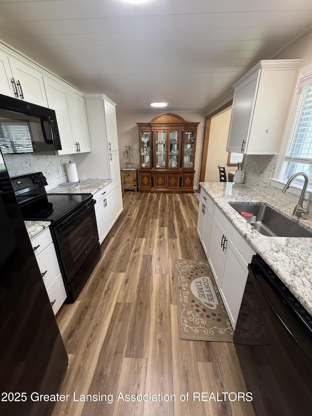 4412 Darron Dr, Lansing, MI 48917 - kitchen featuring black appliances, a sink, light wood finished floors, white cabinets, and backsplash