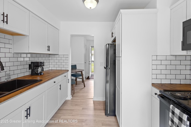 401 Julian Ave, Lansing, MI 48917 - kitchen with wood counters, freestanding refrigerator, light wood-style floors, and a sink