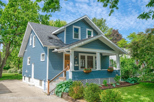 1111 Parkdale Ave, Lansing, MI 48910 - view of front of home with a shingled roof, a garage, concrete driveway, covered porch, and a front lawn