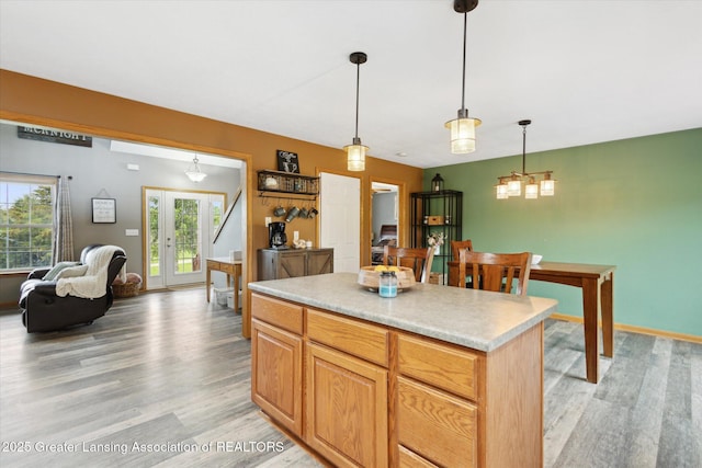 2424 S Canfield Rd, Eaton Rapids, MI 48827 - kitchen with light wood-type flooring, a center island, light countertops, and pendant lighting