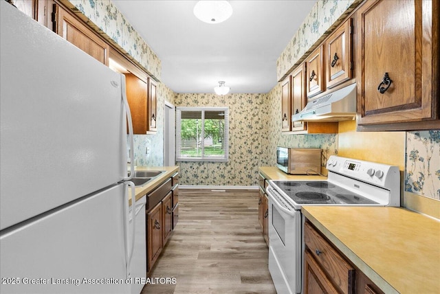 1010 Grenoble Cir, Lansing, MI 48917 - kitchen featuring white appliances, wallpapered walls, under cabinet range hood, light wood finished floors, and brown cabinetry