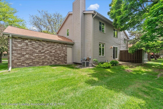 1010 Grenoble Cir, Lansing, MI 48917 - view of side of property with a chimney, a lawn, and brick siding