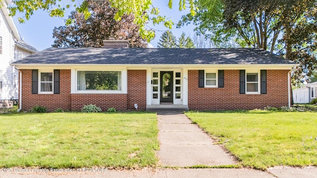415 W Lawrence Ave, Charlotte, MI 48813 - view of front of house featuring a front yard, a chimney, brick siding, and a shingled roof