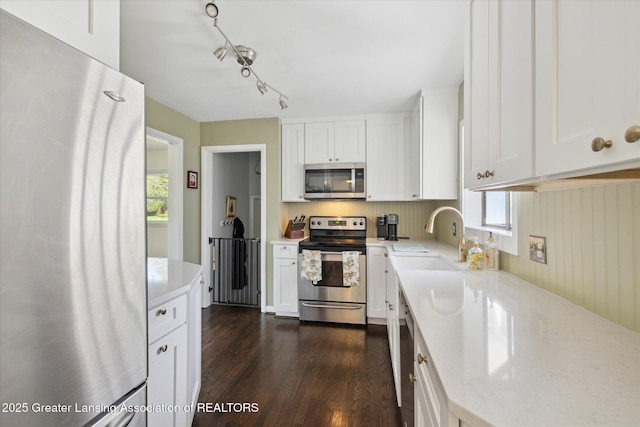 1571 Forest Hills Dr, Okemos, MI 48864 - kitchen with stainless steel appliances, a sink, dark wood-style flooring, white cabinets, and healthy amount of natural light