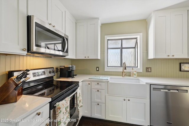 1571 Forest Hills Dr, Okemos, MI 48864 - kitchen featuring stainless steel appliances, a sink, white cabinets, and wooden walls