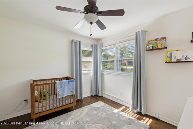 1571 Forest Hills Dr, Okemos, MI 48864 - bedroom with baseboard heating, a nursery area, wood finished floors, baseboards, and a ceiling fan