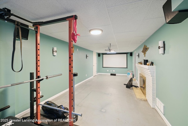 1571 Forest Hills Dr, Okemos, MI 48864 - cinema featuring finished concrete floors, a brick fireplace, a paneled ceiling, and baseboards