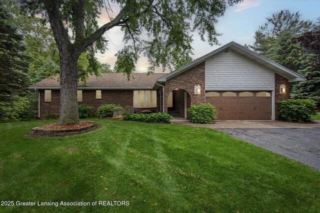 1346 E Howe Rd, Dewitt, MI 48820 - view of front of home with driveway, a garage, brick siding, and a front lawn