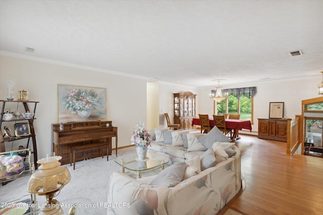 1346 E Howe Rd, Dewitt, MI 48820 - living room featuring a chandelier, ornamental molding, baseboard heating, and light wood finished floors
