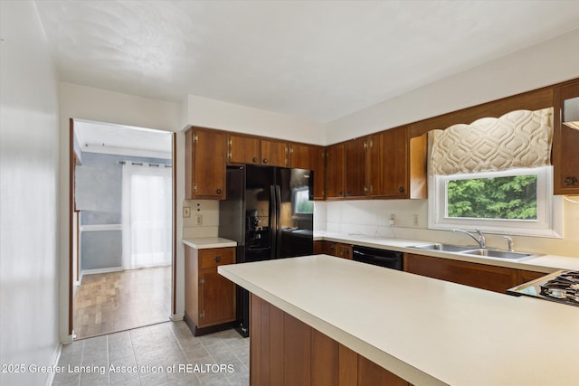 1116 W Service Rd, Mason, MI 48854 - kitchen featuring a sink, dishwasher, light countertops, a peninsula, and brown cabinetry