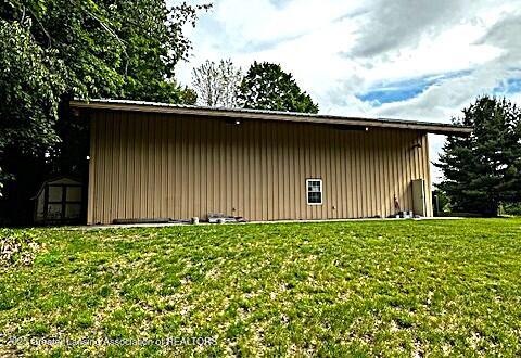 1116 W Service Rd, Mason, MI 48854 - view of side of home featuring board and batten siding, a lawn, and a pole building