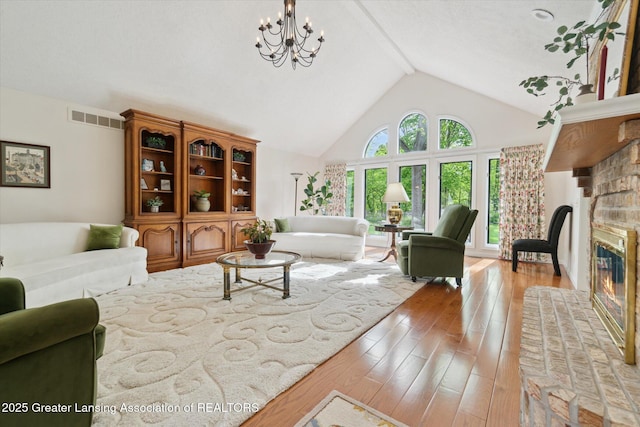 12728 Oneida Woods Trl, Grand Ledge, MI 48837 - living room with a brick fireplace, hardwood / wood-style floors, high vaulted ceiling, and a chandelier