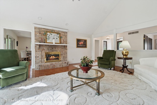12728 Oneida Woods Trl, Grand Ledge, MI 48837 - living area with wood finished floors, a brick fireplace, high vaulted ceiling, healthy amount of natural light, and baseboards