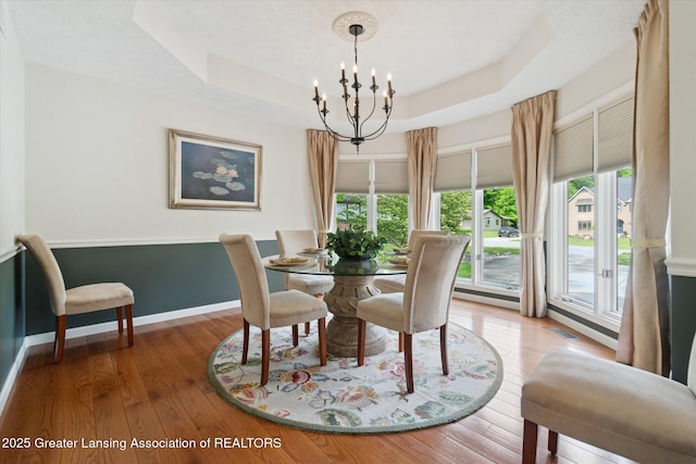12728 Oneida Woods Trl, Grand Ledge, MI 48837 - dining area with a chandelier, baseboards, a raised ceiling, and wood finished floors