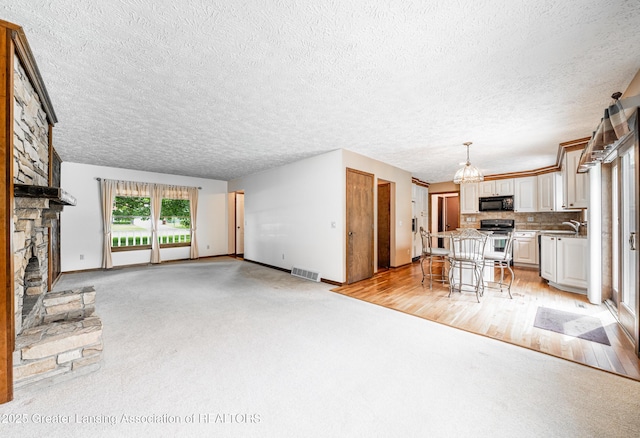 1932 Maple Shade Dr, Williamston, MI 48895 - unfurnished living room featuring a fireplace, a sink, baseboards, a textured ceiling, and a chandelier