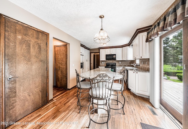 1932 Maple Shade Dr, Williamston, MI 48895 - kitchen featuring black appliances, a sink, a chandelier, light wood-type flooring, and white cabinetry