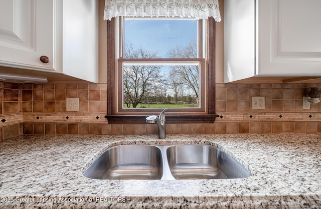 1932 Maple Shade Dr, Williamston, MI 48895 - kitchen view of a sink, light stone countertops, white cabinets, and decorative backsplash