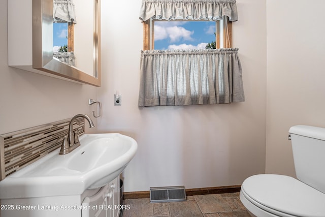 1932 Maple Shade Dr, Williamston, MI 48895 - bathroom featuring baseboards, toilet, vanity, and backsplash