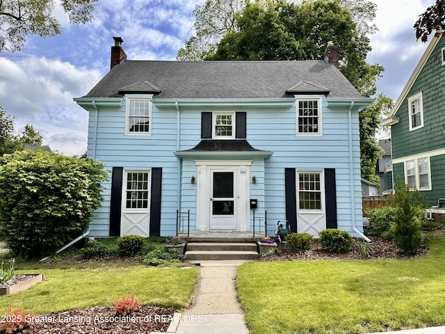 841 Huntington Rd, East Lansing, MI 48823 - view of front of house with a chimney, a front yard, and roof with shingles