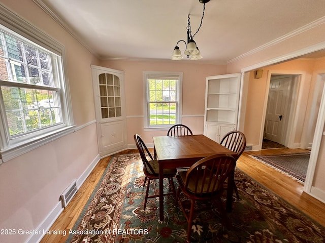 841 Huntington Rd, East Lansing, MI 48823 - dining space featuring a chandelier, light wood-style flooring, ornamental molding, and baseboards
